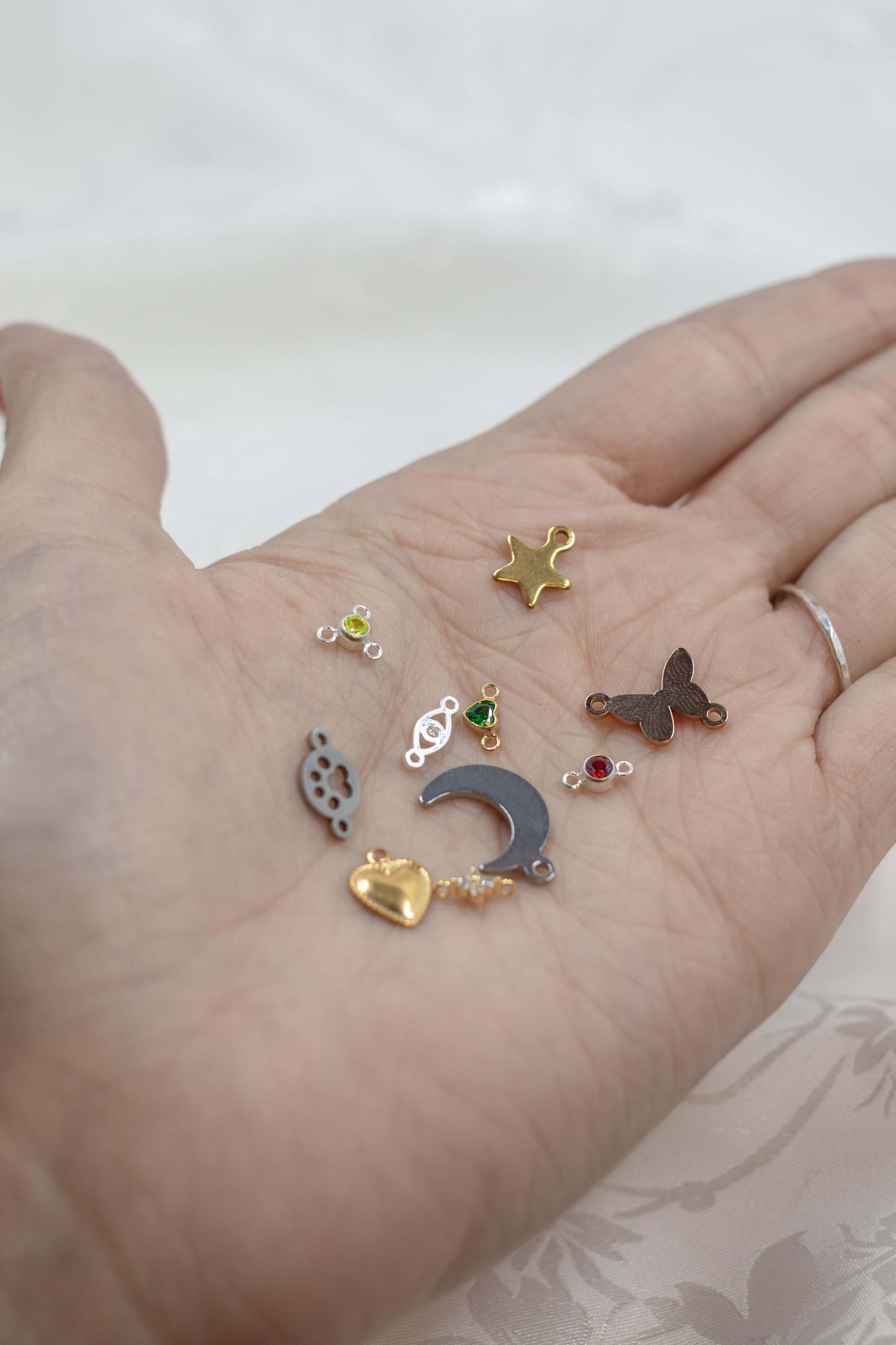 Mystery Charm Box featuring a variety of gold and silver charms displayed on a hand.