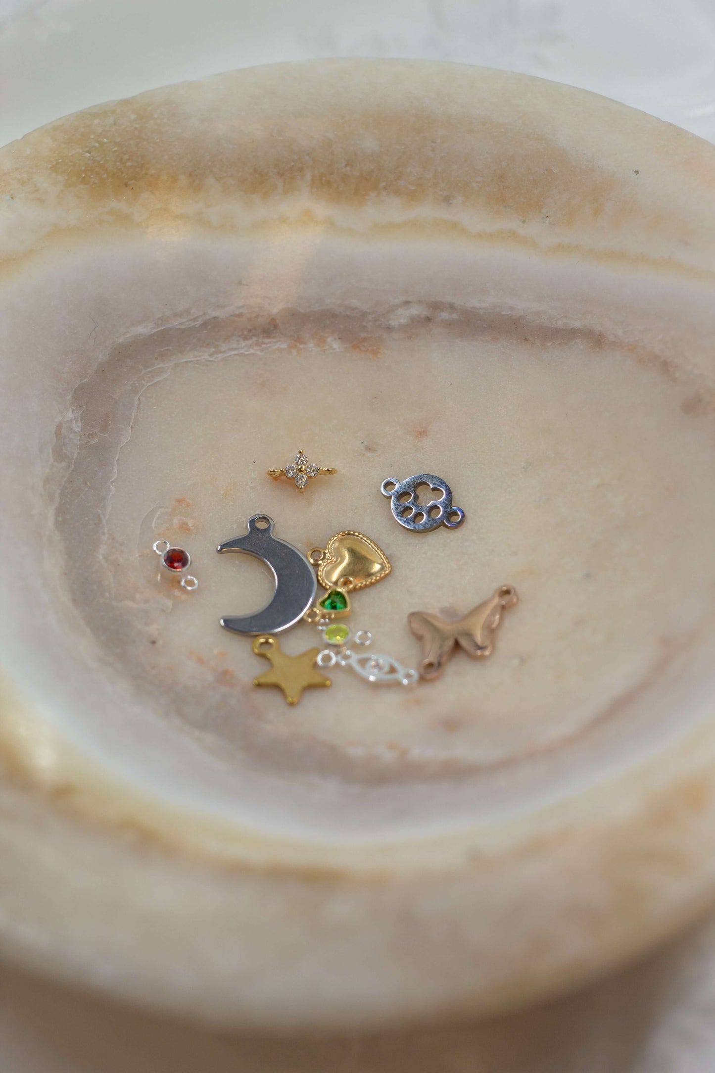 A variety of charms displayed in a bowl, featured in the Mystery Charm Box, showcasing unique designs and styles.