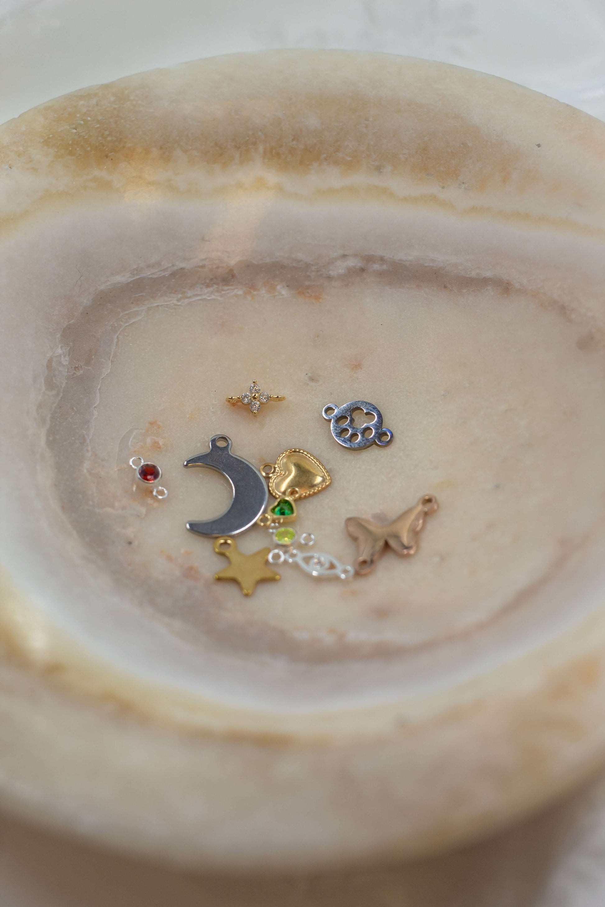 A variety of charms displayed in a bowl, featured in the Mystery Charm Box, showcasing unique designs and styles.